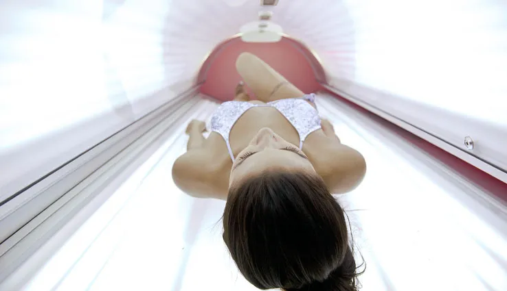 A woman tanning inside of a tanning bed.