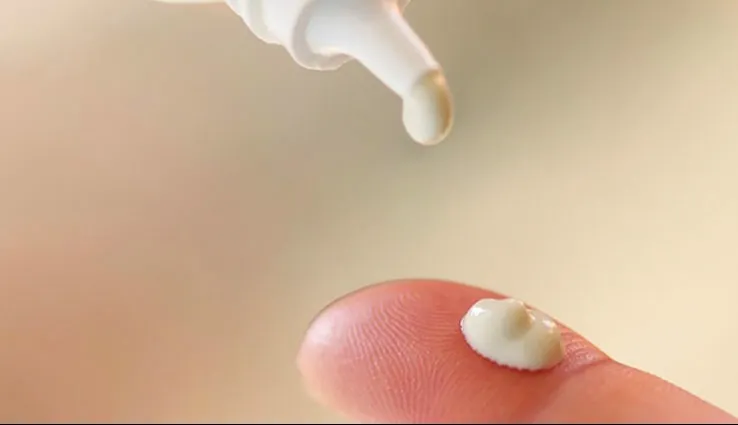 Skincare product being placed on someone's finger tip. 