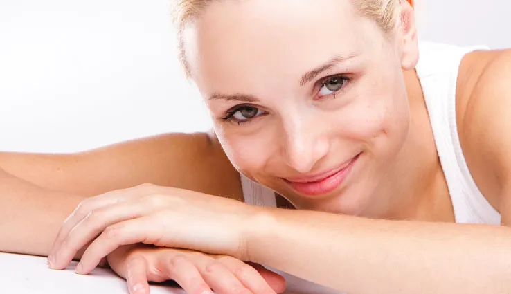 Smiling blonde woman laying her head on her arms.
