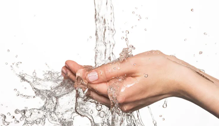 Water pouring onto hands and spilling out and over them.