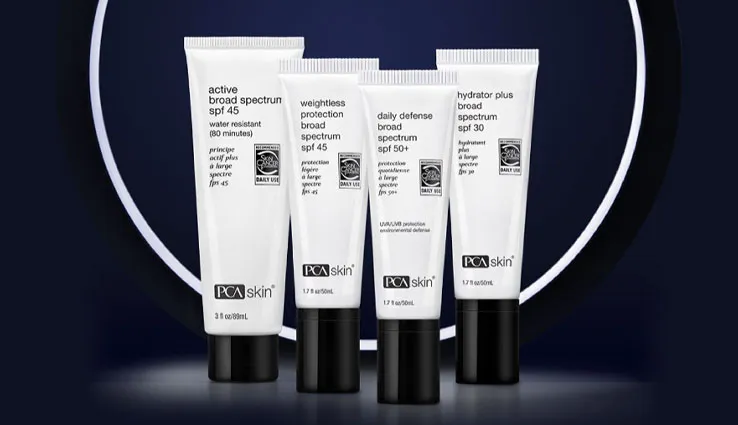 Four of PCA SKIN's sunscreens standing side by side in front of a ring light.
