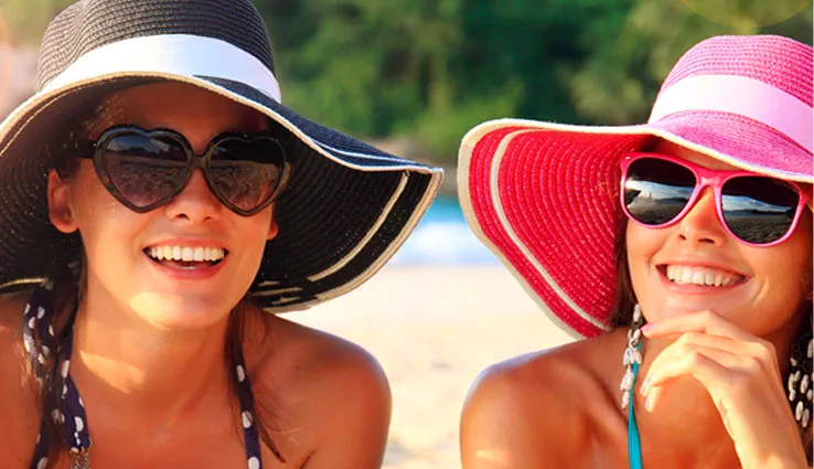 Two women enjoying the summer sun in sun hats and sunglasses.