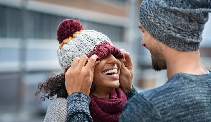 A woman wearing a beanie laughs.