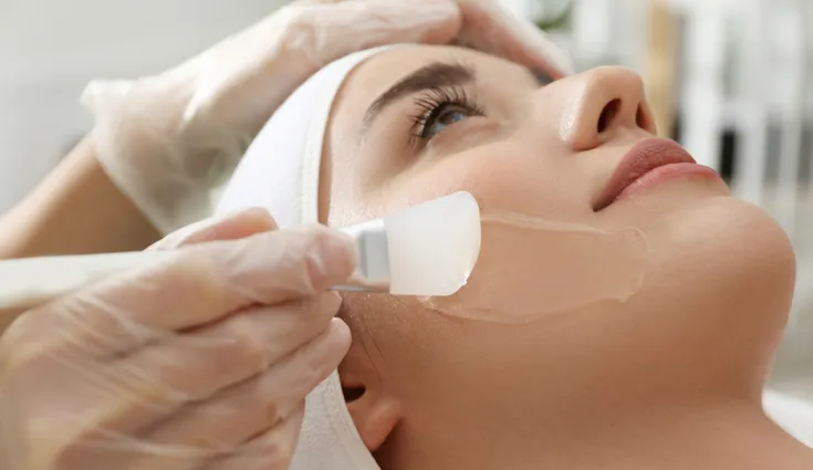 a professional chemical peel is applied to a woman’s face by a professional